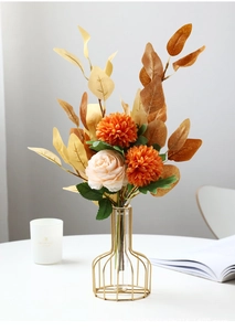 Detail of orange and beige faux flowers in a golden metal cage vase for table decor