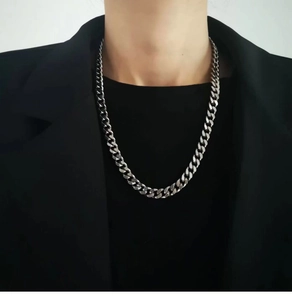 Close-up of a silver Cuban link chain necklace worn by a model in a black suit