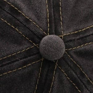 Detail of grey washed denim baseball cap featuring yellow double stitching and top button