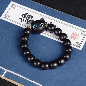 Bracelet en bois de santal avec tête de chat aux yeux bleus sur fond de livre bleu
