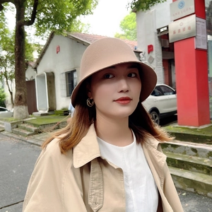 Gros plan extérieur d'un chapeau cloche en laine kaki porté avec un trench assorti