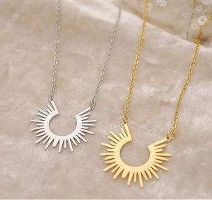 Detail of sunbeam semi-circle necklaces in gold and silver on soft beige velvet