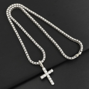 Detail of silver tennis chain and pearl cross pendant with sparkling crystals on black