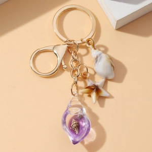 Luminous starfish and seashell keychain with golden clasp on a minimalist beige background