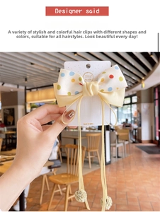 Detail of yellow polka dot bow hair clip with ribbons and soft pompom decor