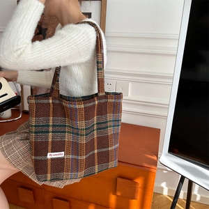 Detail of checkered woolen tote bag showing thick texture and fabric shoulder strap