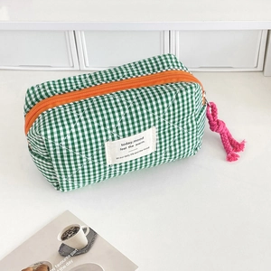 Detail of green gingham storage pouch with orange zipper and vibrant pink pull cord