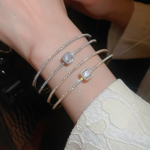 Close-up of gold and silver layered bow bracelets with zircon on a model's wrist