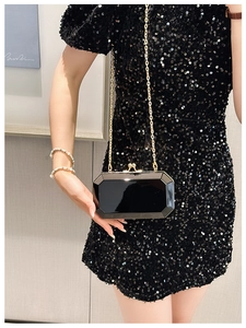 Macro shot of black geometric acrylic clutch bag with gold chain and metal clasp