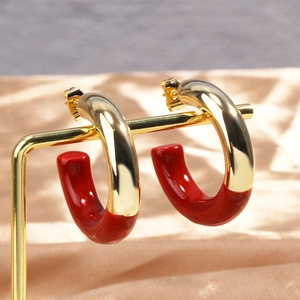 Créoles en C minimalistes dorées et rouges sur une élégante soie couleur champagne