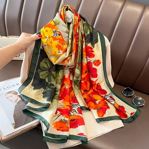 Floral print satin silk scarf with vintage flower patterns on a leather sofa
