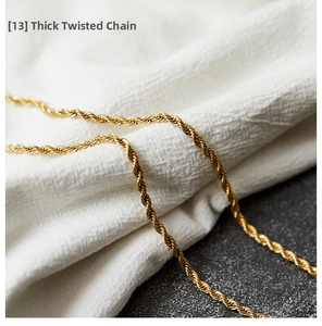 Close-up of a thick gold-plated titanium rope chain necklace on textured stone