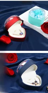 Detail of heart-shaped jewelry box with preserved rose and necklace on blue silk
