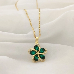 Macro shot of gold necklace with green teardrop crystal flower pendant on silk