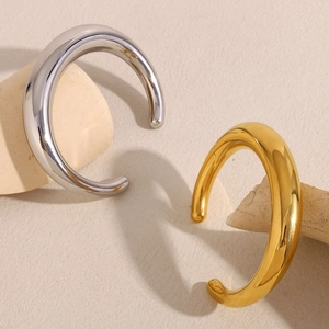 Macro detail of minimalist hollow bangle in polished gold and silver on stone