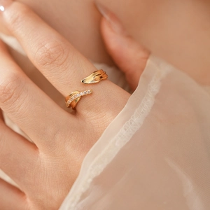 Détail d'une bague dorée au design de feuille sertie de zircons et à anneau ajustable