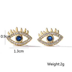 Macro detail of gold-plated evil eye stud earrings with blue zircon and white crystals