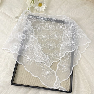 Detailed close-up of white floral lace triangle scarf with delicate scalloped edges