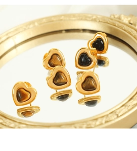 Close-up of heart earrings with tiger eye stone reflected on a gold-rimmed mirror