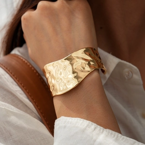 Macro detail of wide hammered gold cuff bracelet with irregular wave texture
