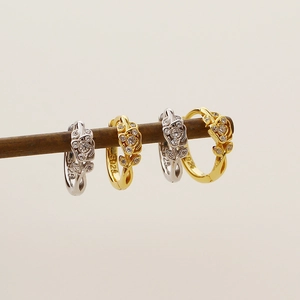 Close-up of S925 sterling silver rose earrings with diamonds in gold and silver