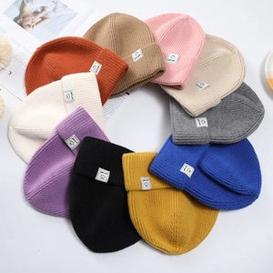 Top-down view of multi-color knitted beanies in a circular layout with smiley face patches