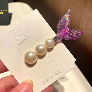 Detail showing mermaid tail hair clip with pearls and sequins on a gold metal base