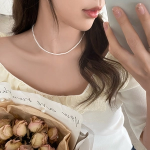 Elegant white pearl necklace worn by a model in a natural mirror selfie setting