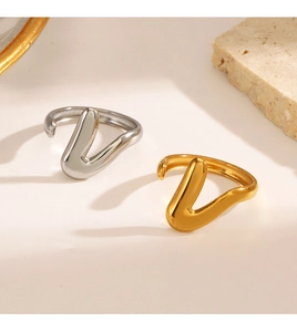 Close-up of minimalist V-shaped 18K gold and silver rings on elegant stone props