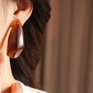 Close-up of elegant amber teardrop resin earring worn by a model with a warm glow