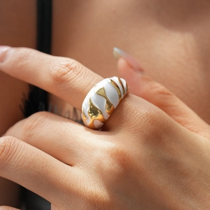 Close-up of wavy gold and white enamel geometric ring on model's hand