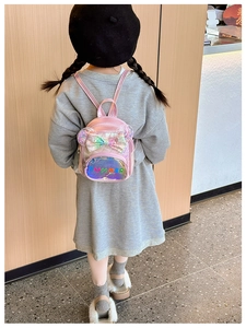 Rear view of a girl wearing a pink holographic bow backpack with shiny sequin ears
