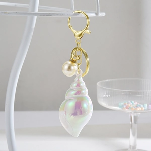 Detail view of colorful iridescent conch keychain with pearl accent on gold hardware
