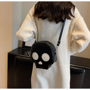 Detailed view of skull-shaped crossbody bag with heart nose and adjustable strap on a model