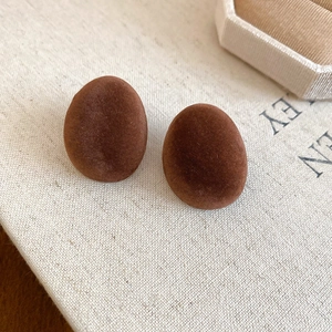 Gros plan de boucles d'oreilles ovales en velours marron au style vintage chic