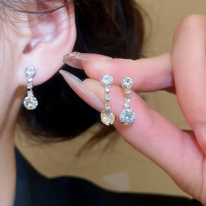 Detail view of sparkling round diamond drop earrings worn by a model in luxury style
