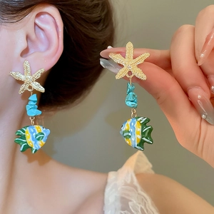 Detail of starfish and turquoise fish earrings worn by model for beach vacation style