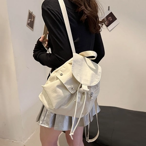 Rear view of a model wearing a minimalist beige nylon mini backpack with flap design