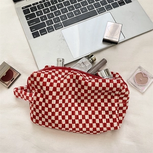 Macro detail of red and white checkered velvet makeup bag with wave texture and zipper