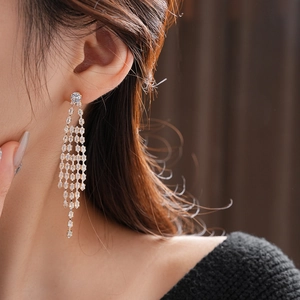 Detail of gold-plated tassel earrings with zircon stones worn by a model