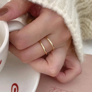 Minimalist gold rings layered styling on hand with coffee cup for winter daily look