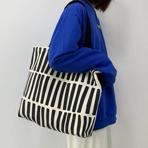 Side view of a large capacity canvas tote bag with black vertical stripes on model