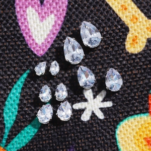 Close-up of sparkling water drop zirconia earrings in various sizes on fabric