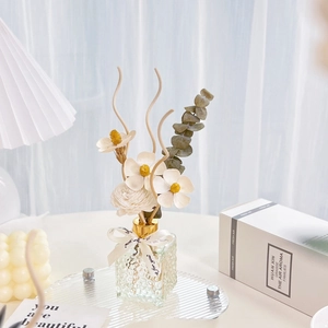 Close-up of reed diffuser with handmade sola flowers and cream ribbon in glass bottle
