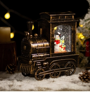 Macro shot of snow globe train with snowman inside on snowy background with warm lights