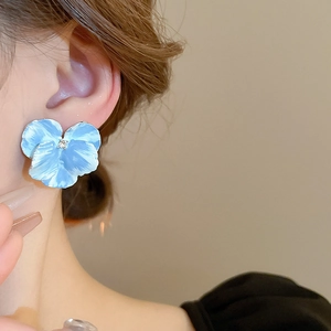 Detailed view of light blue iris flower earrings with delicate center diamond on ear