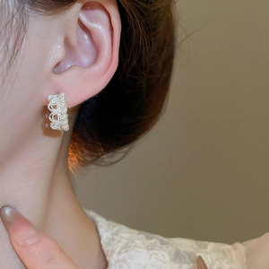 Detail of elegant gold crown earring with two rows of pearls worn by a model