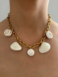 Close-up of a gold chain necklace with natural white seashells on a female neck