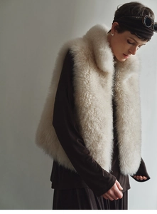 Detail shot of white faux fox fur vest texture paired with brown long sleeve dress