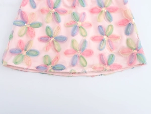 Detail eines rosa Rocks mit handgefertigten 3D-Blumenapplikationen und funkelnden Pailletten